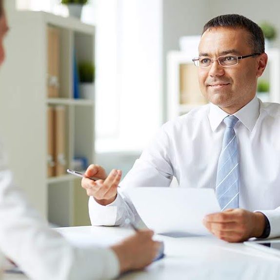 Portrait of mature businessman looking at his secretary while speaking to her